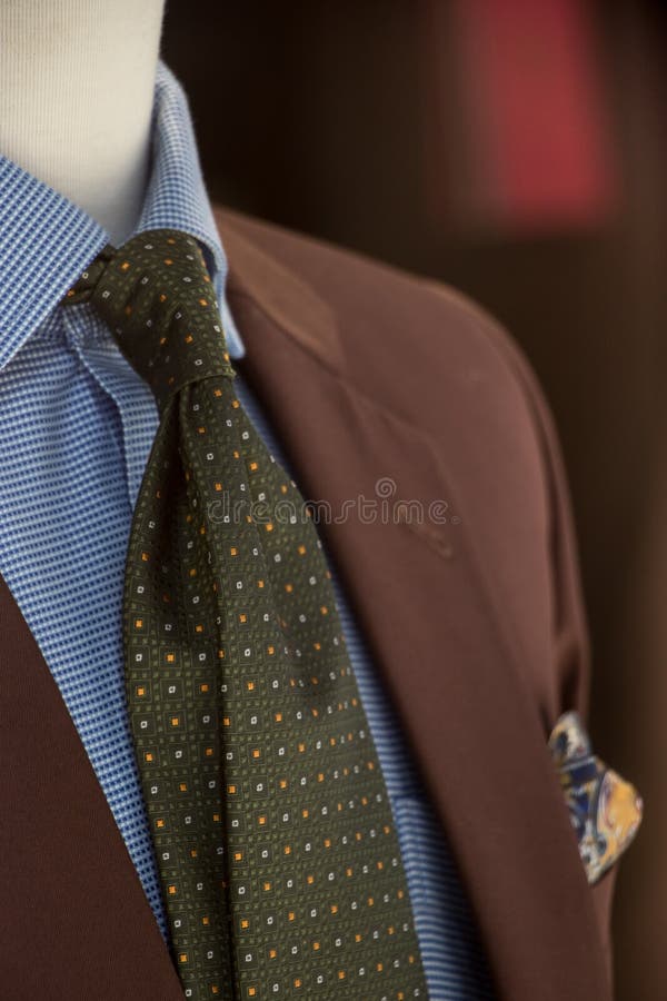 Ventana de la tienda de la tienda para hombre del sastre que muestra un maniquí en una habitación marrón, una camisa azul y un la fotos de archivo libres de regalías Ventana de la tienda de la tienda para hombre del sastre que muestra un maniquí en una habitación marrón, una camisa azul y un la fotos de archivo libres de regalías