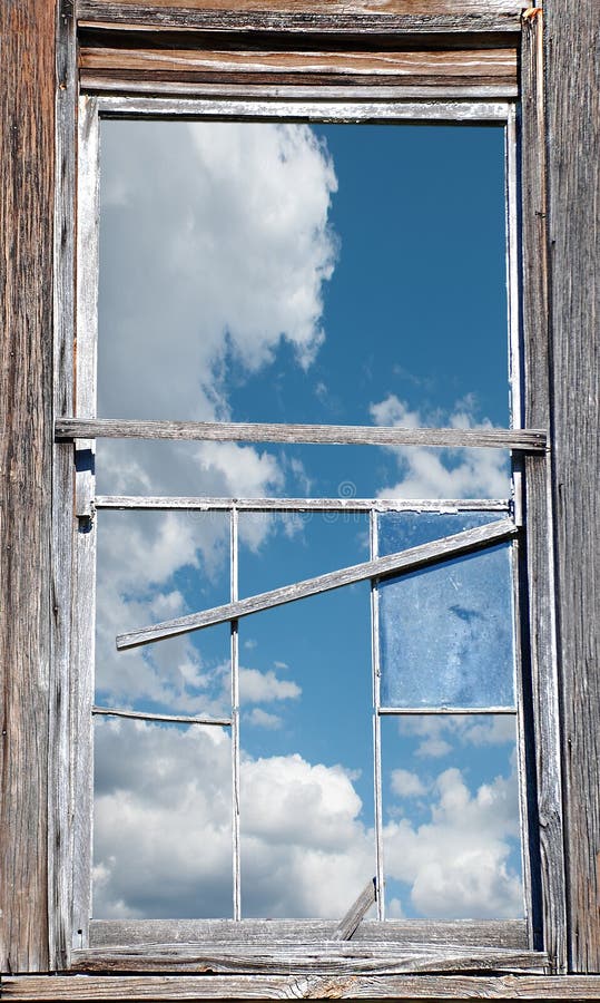 Weathered wood siding and sashes frame a broken and deteriorating 12 pane window. Through the window, one can see a clear optimistic sky. Weathered wood siding and sashes frame a broken and deteriorating 12 pane window. Through the window, one can see a clear optimistic sky.