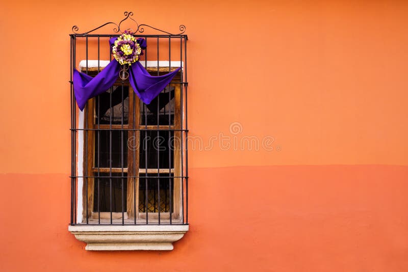 Ventana tradicional en la pared anaranjada con la decoración de la cinta de santa del semana en Antigua, Guatemala foto de archivo Ventana tradicional en la pared anaranjada con la decoración de la cinta de santa del semana en Antigua, Guatemala foto de archivo