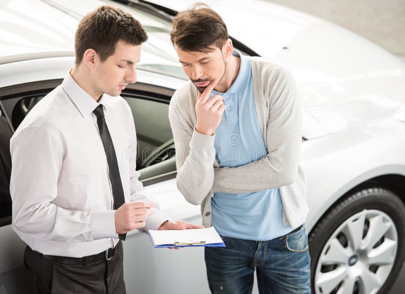 Car salesperson demonstrating a new automobile to young couple. Car salesperson demonstrating a new automobile to young couple.