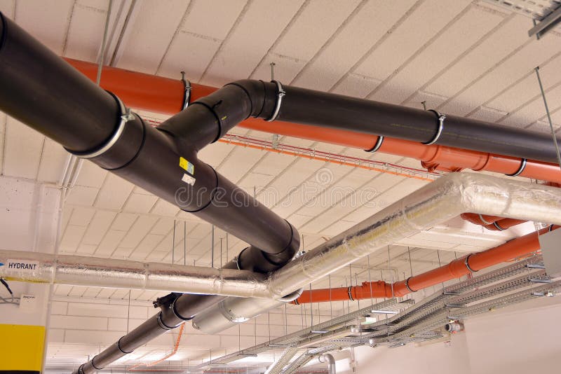 Water Pipes and Cable Trays Run Under Ceiling of a Building Stock Image