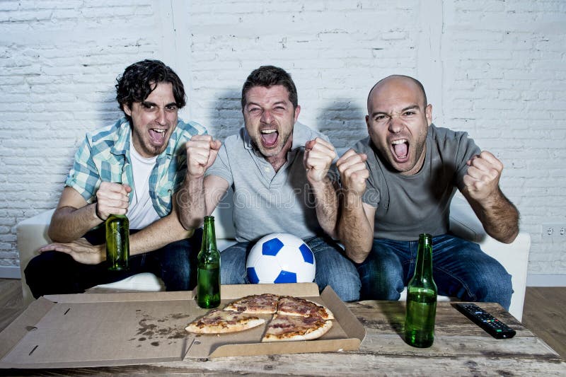 Ventilators die van de vrienden de fanatieke voetbal op spel op TV-het vieren doel letten die gekke gelukkig gillen stock fotografie Ventilators die van de vrienden de fanatieke voetbal op spel op TV-het vieren doel letten die gekke gelukkig gillen stock fotografie