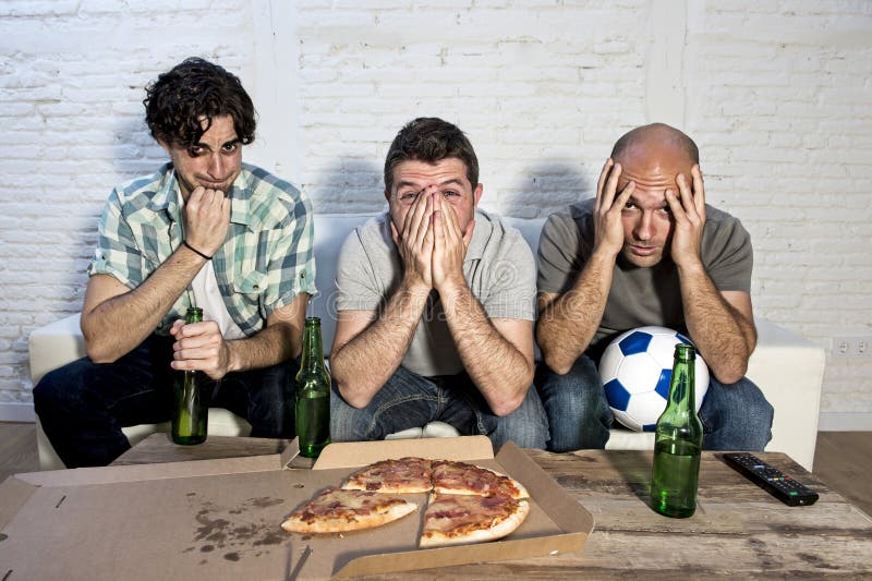 Ventilators die van de vrienden de fanatieke voetbal TV-op gelijke met bierflessen en pizza letten die aan spanning lijden royalty-vrije stock fotografie Ventilators die van de vrienden de fanatieke voetbal TV-op gelijke met bierflessen en pizza letten die aan spanning lijden royalty-vrije stock fotografie