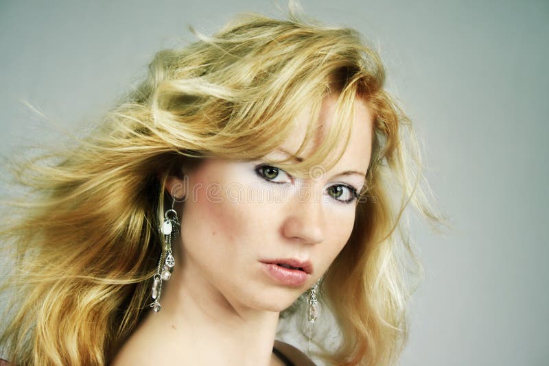 Beauty portrait of a woman with earrings and wind on her hair. Beauty portrait of a woman with earrings and wind on her hair