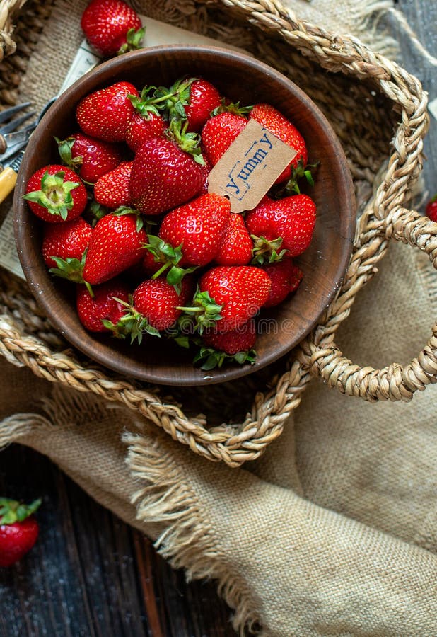 ?ver huvudet skott av smakliga mogna jordgubbar i tr?bunkest?llningar i vide- strawy korg p? den lantliga tabellen fotografering för bildbyråer ?ver huvudet skott av smakliga mogna jordgubbar i tr?bunkest?llningar i vide- strawy korg p? den lantliga tabellen fotografering för bildbyråer