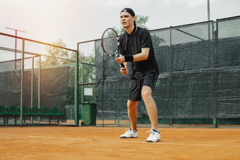 Ver plan van het tennisracket van de mensenholding in beide handen om staking recht te maken royalty-vrije stock foto Ver plan van het tennisracket van de mensenholding in beide handen om staking recht te maken royalty-vrije stock foto