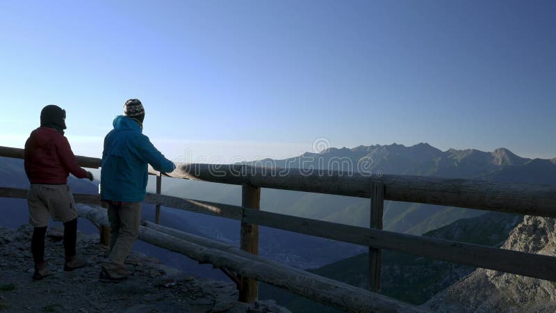 Verbinden Sie das Gehen zum hölzernen Balkon und das Betrachten des Bergblicks bei dem Sonnenaufgang, der oben auf den Alpen hoch