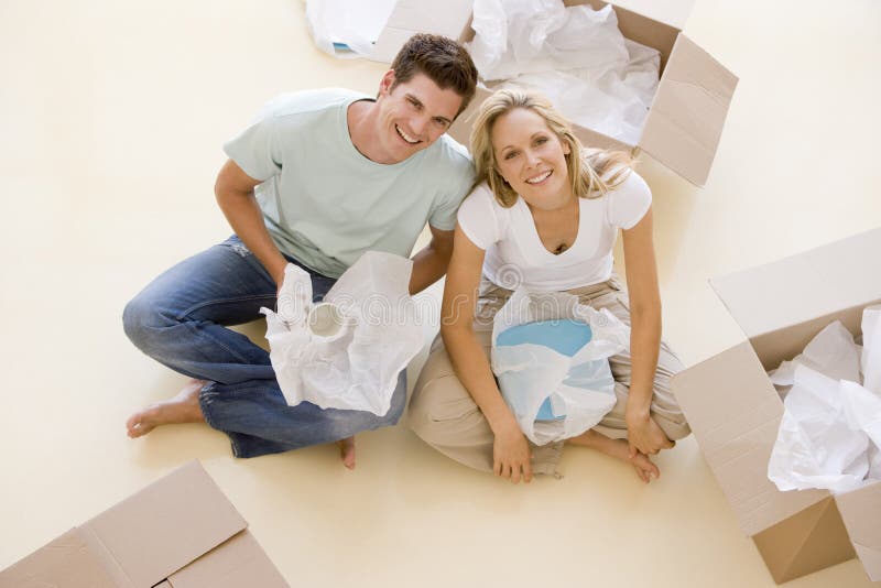 Verbinden Sie das Sitzen auf Fußboden durch geöffnete Kästen im neuen Haus lizenzfreie stockbilder Verbinden Sie das Sitzen auf Fußboden durch geöffnete Kästen im neuen Haus lizenzfreie stockbilder