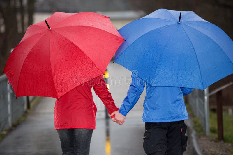 Verbinden Sie Hand in Hand Weg im Regen mit Regenschirm stockbilder Verbinden Sie Hand in Hand Weg im Regen mit Regenschirm stockbilder