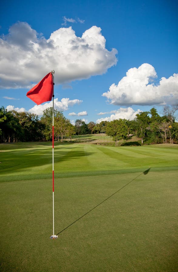 Campo de golfe verde com uma bandeira vermelha a acenar foto de stock