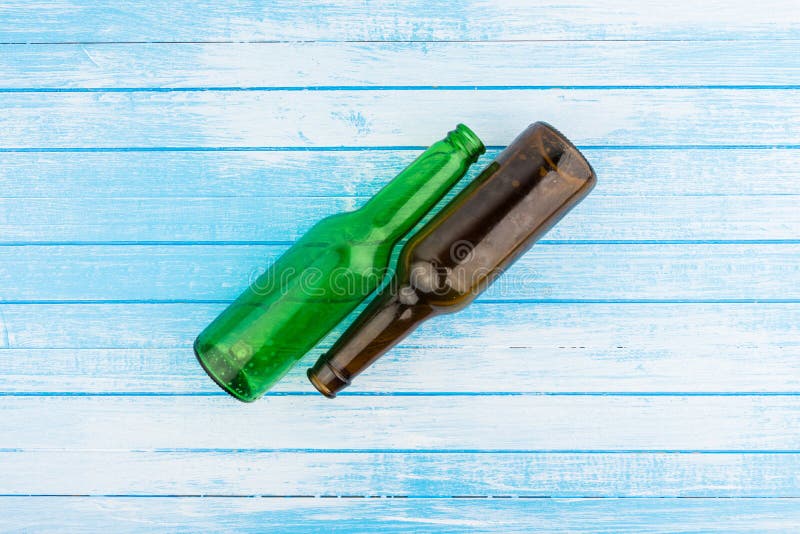 Verde e bottiglie di birra vuote di Brown sulle sedere di legno dipinte bianco blu fotografia stock Verde e bottiglie di birra vuote di Brown sulle sedere di legno dipinte bianco blu fotografia stock