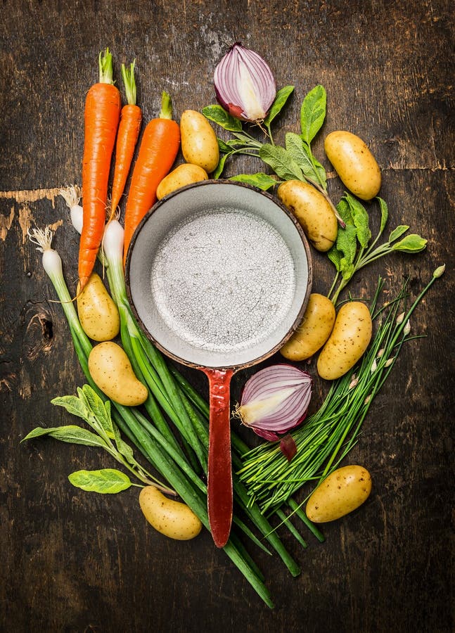 Verduras e hierbas orgánicas frescas alrededor del pote de cocinar vacío viejo en el fondo de madera rústico, el componer de la v fotos de archivo libres de regalías Verduras e hierbas orgánicas frescas alrededor del pote de cocinar vacío viejo en el fondo de madera rústico, el componer de la v fotos de archivo libres de regalías