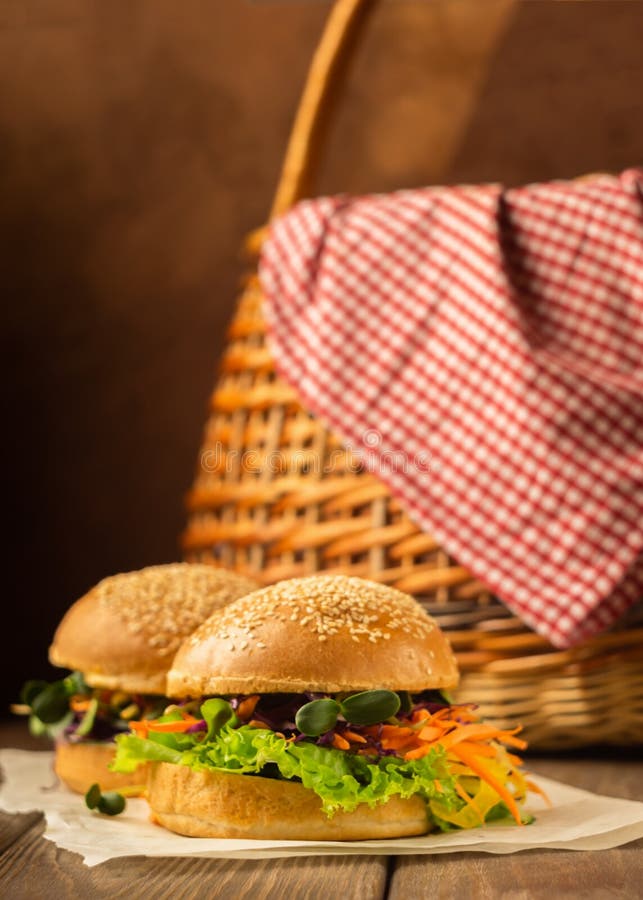 Verduras frescas de la hamburguesa del vegano: zanahorias, fondo rústico de madera oscuro de los verdes jovenes de los brotes de foto de archivo Verduras frescas de la hamburguesa del vegano: zanahorias, fondo rústico de madera oscuro de los verdes jovenes de los brotes de foto de archivo