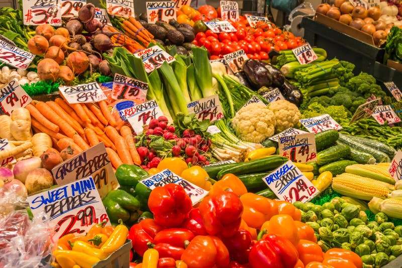 A close up view of a colorful display of a large variety of fresh vegetables with handmade signs identifying their names and prices at a stand in a farmers market in a tourist area. A close up view of a colorful display of a large variety of fresh vegetables with handmade signs identifying their names and prices at a stand in a farmers market in a tourist area.