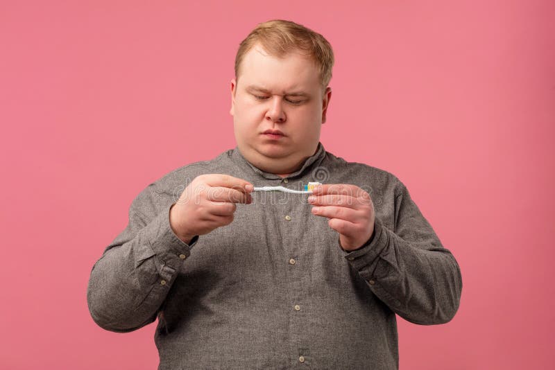 Verdächtiger skeptischer Mann hält Zahnbürste, in der Hand um Zahngesundheit kümmern. lizenzfreie stockfotografie