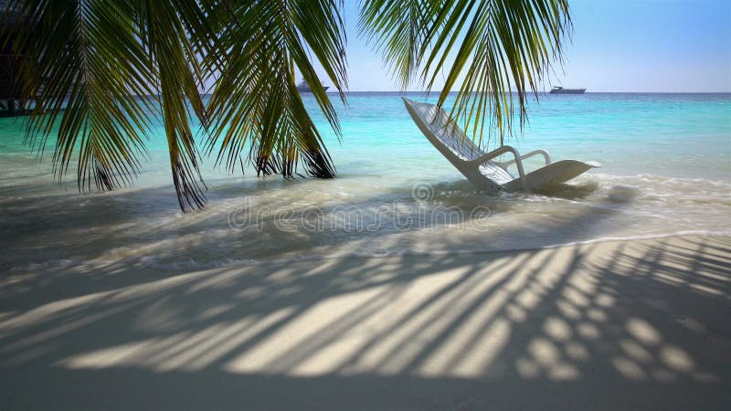 Vergessener Strandstuhl auf dem tropischen Strand in den Meereswogen