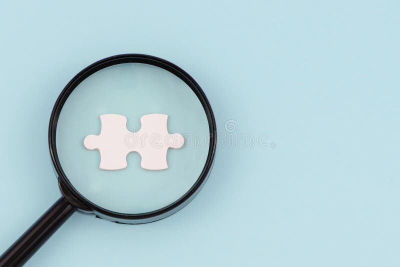 Vergrootglas die naar het missen van raadselstukken zoeken op lichtblauwe achtergrond De ruimte van het exemplaar stock afbeelding Vergrootglas die naar het missen van raadselstukken zoeken op lichtblauwe achtergrond De ruimte van het exemplaar stock afbeelding