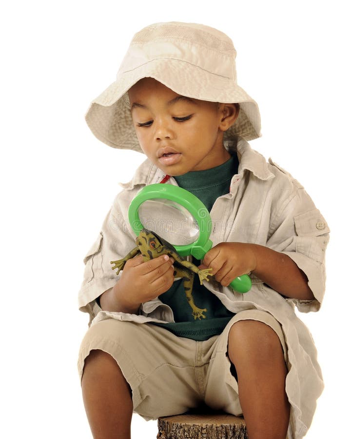 An adorable preschooler in a safari hat and explorer clothes examining a frog's belly with a magnifying glass. An adorable preschooler in a safari hat and explorer clothes examining a frog's belly with a magnifying glass.