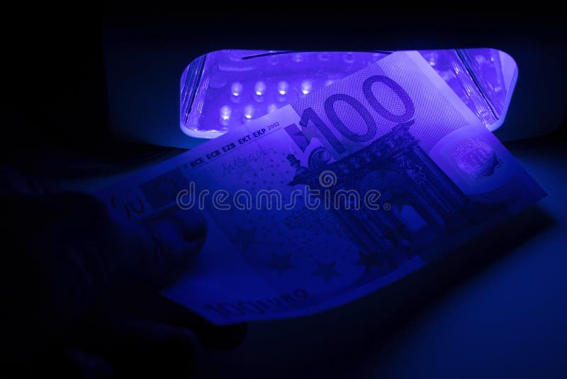 Verification of a banknote of 100 euros on a device for detecting fakes through ultraviolet light. Counterfeiting of banknotes stock image