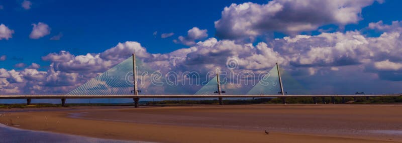 Traffic drives across the bridge which spans across the River Mersey whilst the tide is out and you cans ee the sand. Traffic drives across the bridge which spans across the River Mersey whilst the tide is out and you cans ee the sand