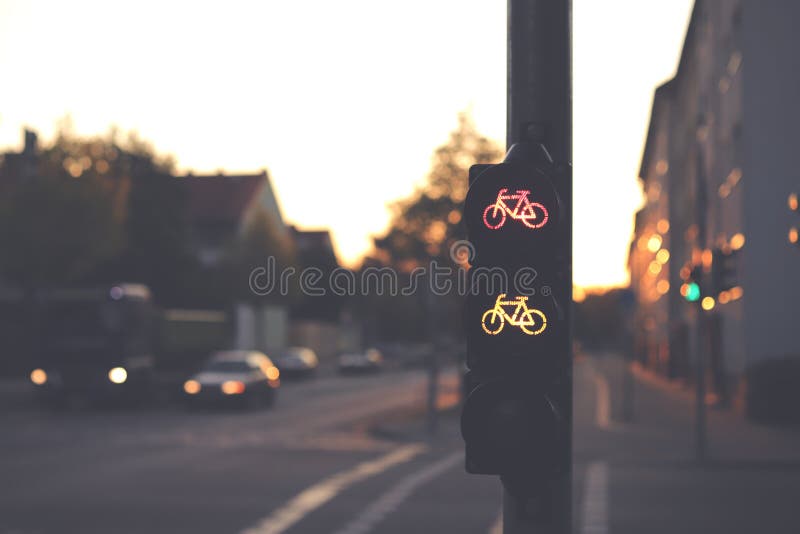 verkeerslicht voor een rijstrook met rood en geel fietssymbool op een veelvuldig kruispunt in donker vroege ochtendlicht