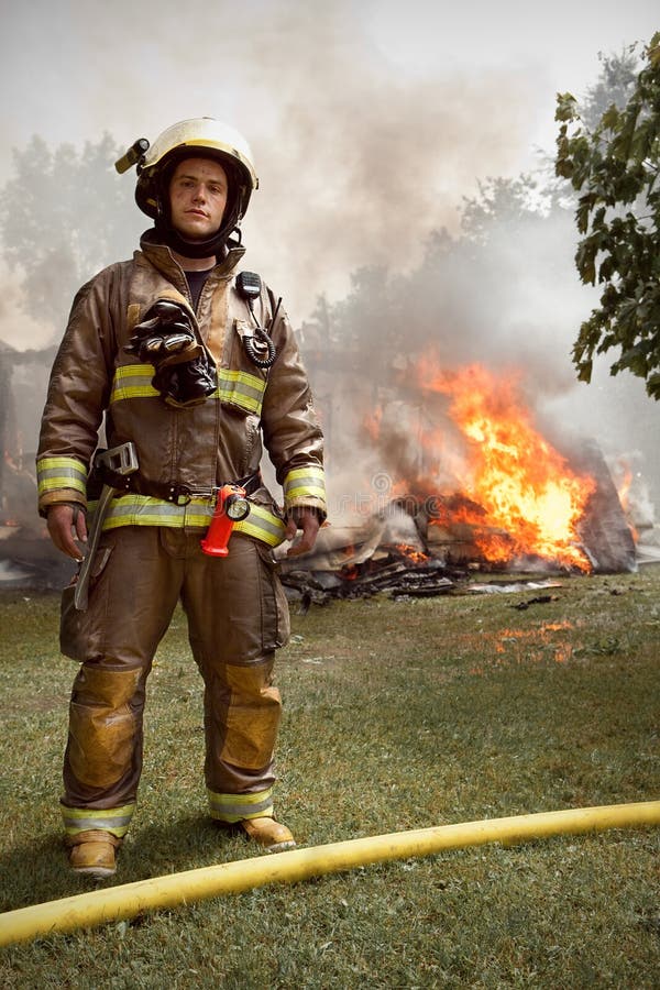 Verklig brandman med huset på brand i bakgrund royaltyfri foto Verklig brandman med huset på brand i bakgrund royaltyfri foto