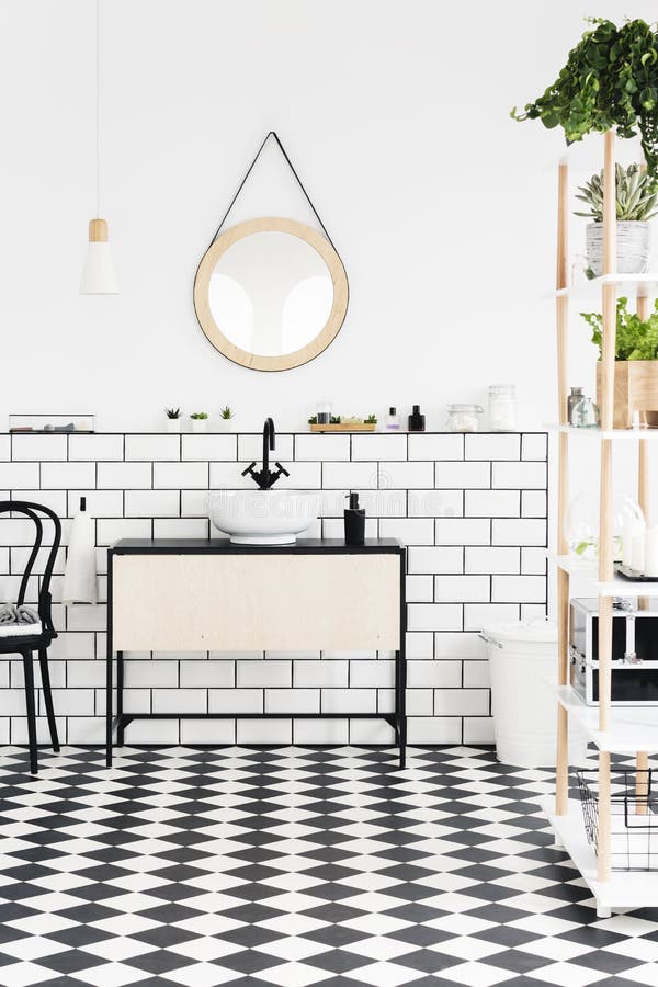 Verkligt foto av en modern badruminre med det rutiga golvet, spegeln, tvättställen med ett skåp och växter arkivfoto Verkligt foto av en modern badruminre med det rutiga golvet, spegeln, tvättställen med ett skåp och växter arkivfoto