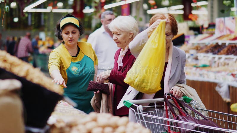 Verkoper geeft tas met koop aan oudere vrouwen op de markt