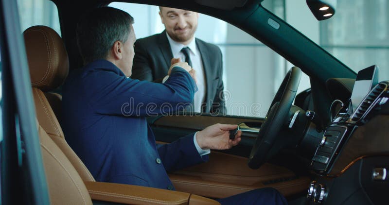 Verkoper het schudden hand aan koper binnen nieuwe auto stock foto Verkoper het schudden hand aan koper binnen nieuwe auto stock foto