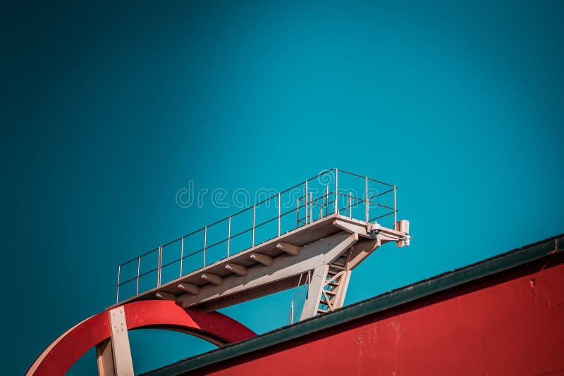 Verlaten metaal het duiken structuur Iconische industriële en sportenarchitectuur, witte en rode staalelementen op een diepe blau royalty-vrije stock afbeelding Verlaten metaal het duiken structuur Iconische industriële en sportenarchitectuur, witte en rode staalelementen op een diepe blau royalty-vrije stock afbeelding