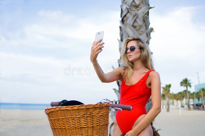 Verlockende Frau in der Badebekleidung, die Selbstporträt mit intelligentem Telefon auf dem Strand nimmt stockbild Verlockende Frau in der Badebekleidung, die Selbstporträt mit intelligentem Telefon auf dem Strand nimmt stockbild