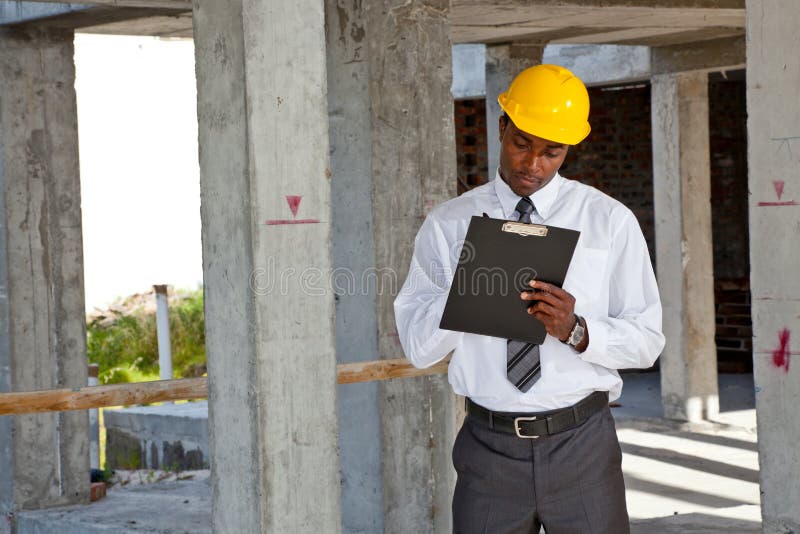 African man inspecting a building site wearing a hard hat. African man inspecting a building site wearing a hard hat