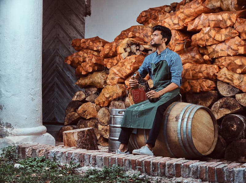 Vermoeide brouwer in schortzitting op vat en van de drankenambacht bier het ontspannen na het werk stock foto's Vermoeide brouwer in schortzitting op vat en van de drankenambacht bier het ontspannen na het werk stock foto's