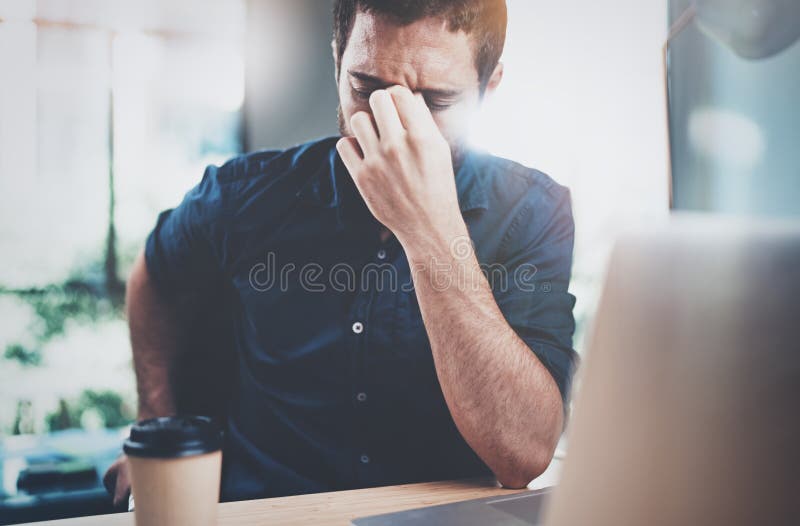 Vermoeide jonge mens die pauze na het harde werkdag maken Medewerker het werk proces op zonnig kantoor horizontaal Vage achtergro royalty-vrije stock afbeelding Vermoeide jonge mens die pauze na het harde werkdag maken Medewerker het werk proces op zonnig kantoor horizontaal Vage achtergro royalty-vrije stock afbeelding