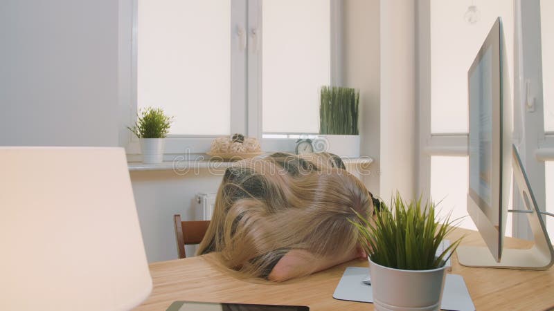 Vermoeide vrouwenontwaken op het werk Vermoeide blonde vrouwelijke beambte in het elegante kostuum ontspannen die op wapens op bu