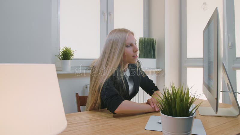 Vermoeide vrouwenontwaken op het werk Vermoeide blonde vrouwelijke beambte in het elegante kostuum ontspannen die op wapens op bu