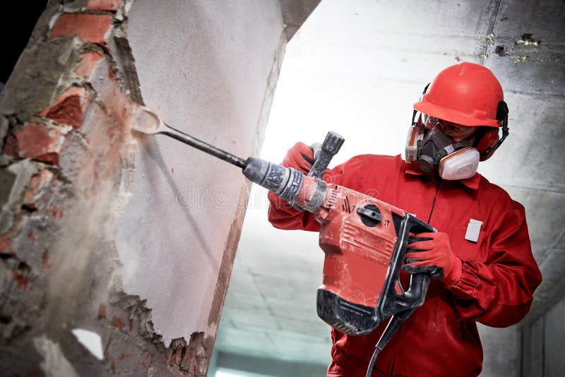 Vernieling en bouw het vernietigen arbeider met hamer die het binnenlandse muur pleisteren breken