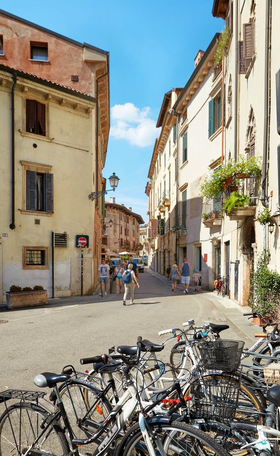 VERONA, ITALIA - 17 AGOSTO 2017: Via stretta di Verona con le biciclette parcheggiate fotografia stock VERONA, ITALIA - 17 AGOSTO 2017: Via stretta di Verona con le biciclette parcheggiate fotografia stock