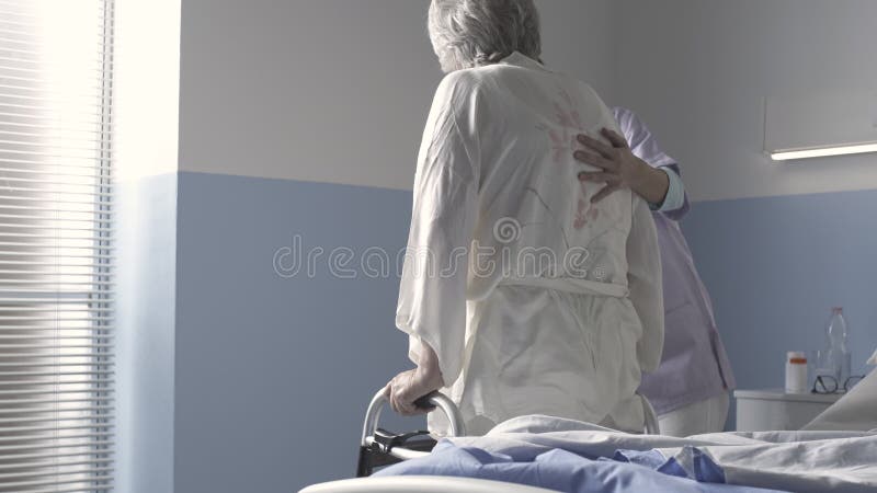 Verpleegkundige die een oudere vrouw in het ziekenhuis helpt
