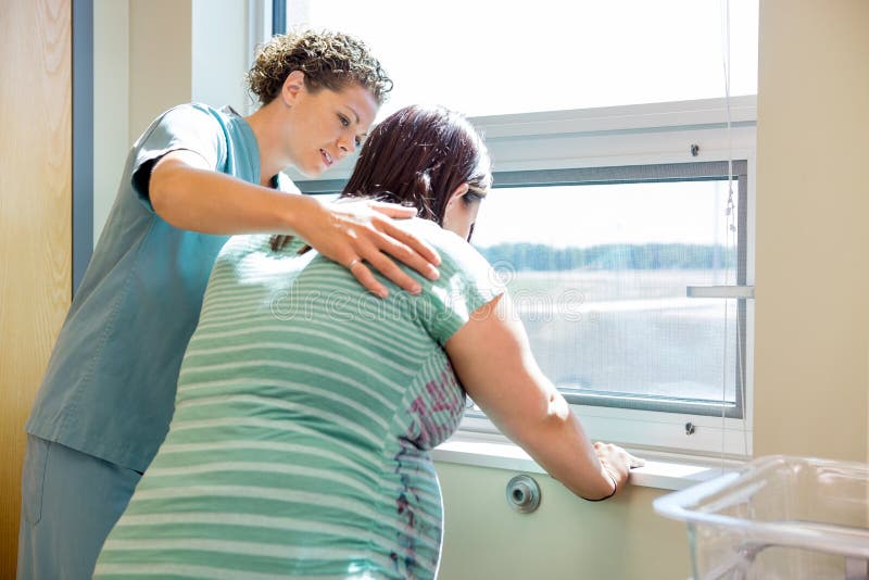Verpleegster Comforting Tensed Pregnant bij Venster binnen