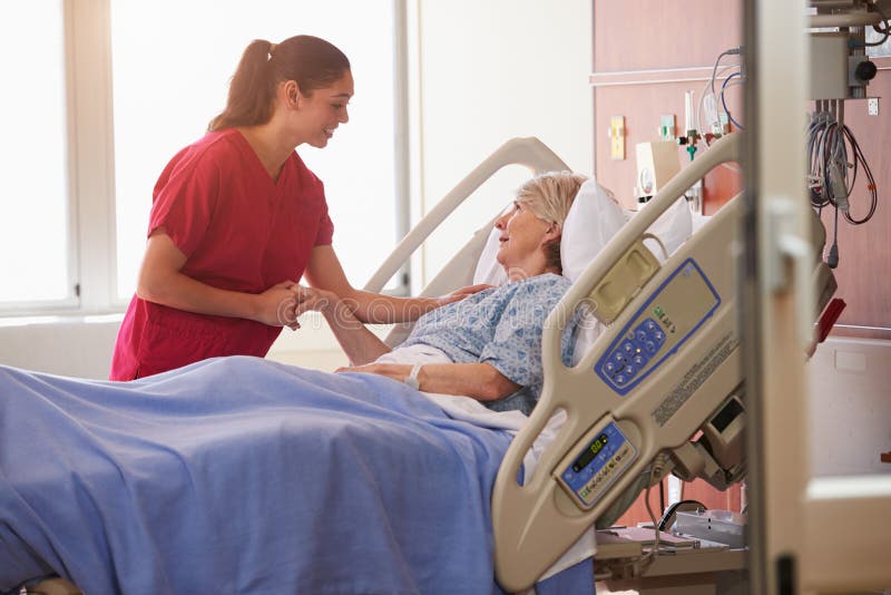 Nurse Talking To Senior Female Patient In Hospital Bed. Nurse Talking To Senior Female Patient In Hospital Bed