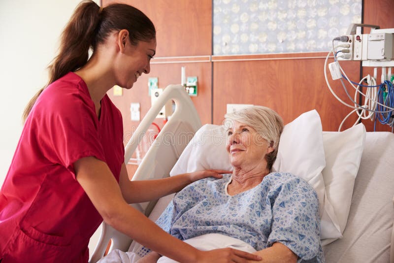 Nurse Talking To Senior Female Patient In Hospital Bed. Nurse Talking To Senior Female Patient In Hospital Bed