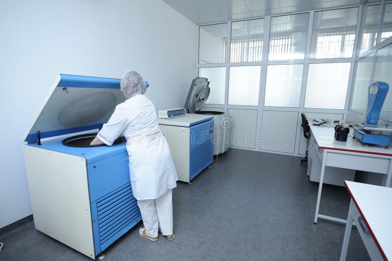 Verpleegster die containers met bloed plaatsen in een centrifuge stock fotografie Verpleegster die containers met bloed plaatsen in een centrifuge stock fotografie