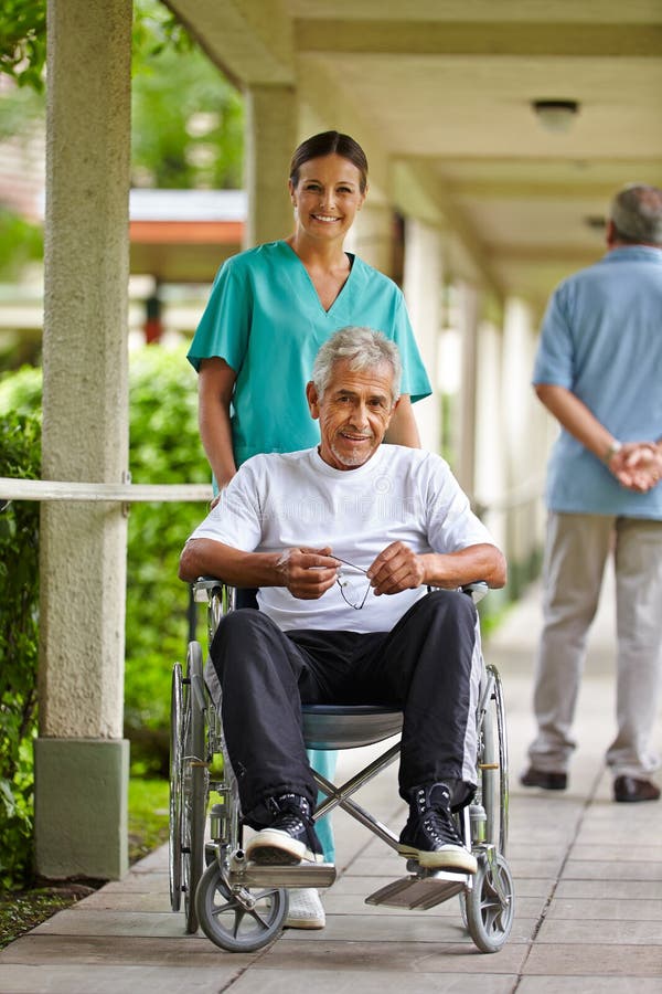 Happy nurse driving a senior men in wheelchair in a clinic. Happy nurse driving a senior men in wheelchair in a clinic