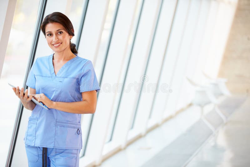 Verpleegster die Digitale Tablet in Gang van het Moderne Ziekenhuis gebruiken