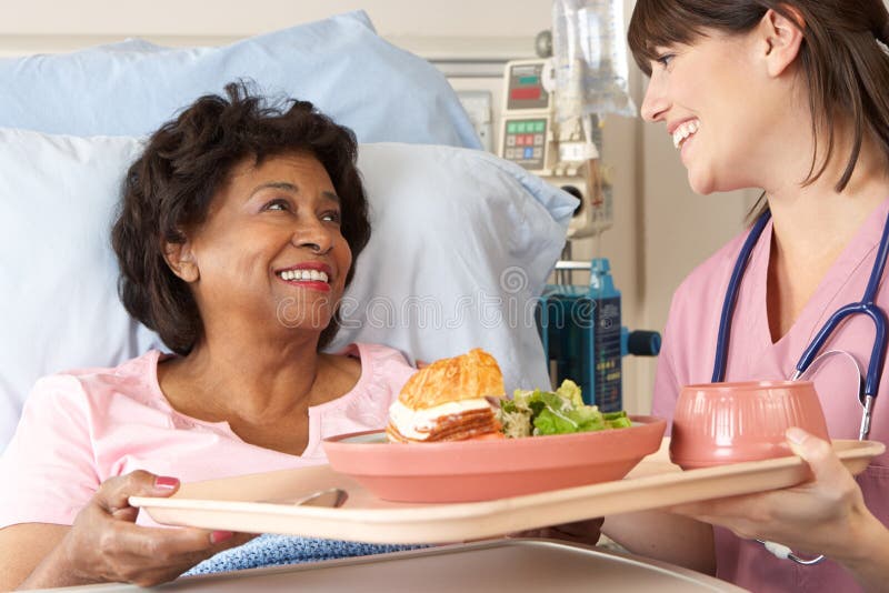 Nurse Serving Senior Female Patient Meal In Hospital Bed Smiling. Nurse Serving Senior Female Patient Meal In Hospital Bed Smiling