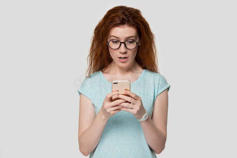 Verrast de holdingssmartphone gelezen onverwacht bericht van het roodharigemeisje stock afbeelding Verrast de holdingssmartphone gelezen onverwacht bericht van het roodharigemeisje stock afbeelding