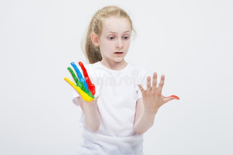 Verrast Jong Meisje die Slordige Kleurrijke Handen bekijken die helder tijdens Verfambacht worden geschilderd Tegen wit stock fotografie Verrast Jong Meisje die Slordige Kleurrijke Handen bekijken die helder tijdens Verfambacht worden geschilderd Tegen wit stock fotografie