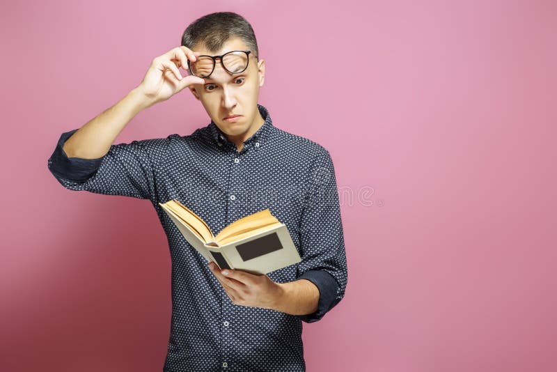 Verraste mens die een boek op een roze achtergrond lezen royalty-vrije stock afbeeldingen Verraste mens die een boek op een roze achtergrond lezen royalty-vrije stock afbeeldingen
