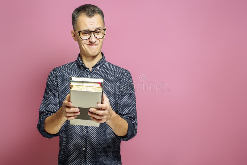 Verraste mens met een stapel boeken op een roze achtergrond stock afbeeldingen Verraste mens met een stapel boeken op een roze achtergrond stock afbeeldingen